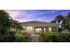 The back exterior of the home featuring a screened-in lanai surrounded by lush landscaping at 12127 Granite Woods Loop, Venice, FL 34292