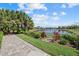 Scenic backyard view of a lake framed by lush greenery and a paved patio at 12127 Granite Woods Loop, Venice, FL 34292