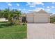 Inviting home exterior with a brick driveway, two-car garage, and lush tropical landscaping at 12127 Granite Woods Loop, Venice, FL 34292
