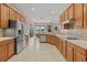 Well-lit kitchen featuring stainless steel appliances, wooden cabinets, and tile flooring at 12127 Granite Woods Loop, Venice, FL 34292