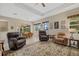 Open living area with three armchairs, a large area rug, and a dining area with outdoor access at 12127 Granite Woods Loop, Venice, FL 34292