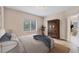 Comfortable staged bedroom with jute rug, ample light, and rustic armoire at 12198 Sebring Ln, Venice, FL 34293