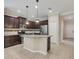 Well-lit kitchen featuring stainless appliances, granite counters, tile backsplash, island with bar seating, and dark wood cabinets at 12198 Sebring Ln, Venice, FL 34293
