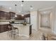 Well-lit kitchen featuring stainless appliances, granite counters, tile backsplash, island with bar seating, and dark wood cabinets at 12198 Sebring Ln, Venice, FL 34293