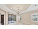 Bright living room featuring tray ceilings, large windows, and sliding glass doors to patio at 12198 Sebring Ln, Venice, FL 34293