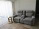 Cozy living room featuring a gray two-seater sofa with recliner, side table and a cream colored lamp at 1255 Tarpon Center Dr # 503, Venice, FL 34285