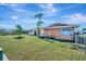 Manicured backyard with lush lawn, shade trees and a garden bed, enclosed by chain-link fence at 13534 Alberta Ave, Port Charlotte, FL 33981