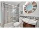 Cozy bathroom boasts a bathtub with shower and a round mirror over the vanity with accenting mosaic tile at 13534 Alberta Ave, Port Charlotte, FL 33981