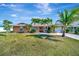 Charming single-story home with a well-manicured lawn, palm trees, and a welcoming facade under a sunny sky at 13534 Alberta Ave, Port Charlotte, FL 33981