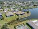 An aerial view of a house with a well-maintained lawn situated near a pond within a residential area at 1602 Jim Jim Ct, Venice, FL 34293