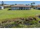 A large backyard with lush green grass, manicured bushes, with a view of the pond at 1602 Jim Jim Ct, Venice, FL 34293