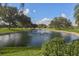 Peaceful pond featuring a fountain, green grass, and mature trees in a well-manicured landscape at 1602 Jim Jim Ct, Venice, FL 34293