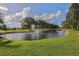 Scenic pond with a fountain, surrounded by lush landscaping and mature trees at 1602 Jim Jim Ct, Venice, FL 34293