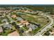 Aerial view of a sprawling community with multiple ponds, mature trees, and vibrant tiled roofs at 1662 Bobcat Trl, North Port, FL 34288