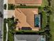 Aerial top down of a home with clay tile roof, solar panels and screened-in pool area with lush backyard at 1662 Bobcat Trl, North Port, FL 34288