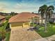 Stunning exterior view of a yellow home showcasing a well-manicured lawn, clay tile roof, and a spacious brick driveway at 1662 Bobcat Trl, North Port, FL 34288