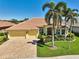 A picturesque exterior showcases a yellow home featuring palm trees, brick driveway, lush landscaping, and a clay tile roof at 1662 Bobcat Trl, North Port, FL 34288