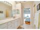 Bright bathroom with double sink vanity, tile flooring, and a view to the bedroom at 1683 San Silvestro Dr, Venice, FL 34285