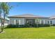 Well-manicured backyard with a screened-in patio and lush landscaping under a blue sky at 16848 Cayo Key Dr, Port Charlotte, FL 33953