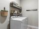 Well-organized laundry room with front loading washer and dryer and decorative floating shelves at 16848 Cayo Key Dr, Port Charlotte, FL 33953