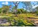 Grassy backyard with a fire pit surrounded by trees, offering a serene outdoor space at 1785 Bayshore Dr, Englewood, FL 34223