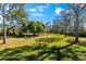 Spacious grassy backyard featuring a fire pit and seating area surrounded by trees at 1785 Bayshore Dr, Englewood, FL 34223