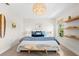 Airy bedroom showcasing a king-size bed with blue accents, stylish lighting, and wood shelving at 1785 Bayshore Dr, Englewood, FL 34223
