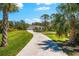Beautiful home on a large lot, featuring lush landscaping and a long driveway, surrounded by mature trees and blue skies at 1785 Bayshore Dr, Englewood, FL 34223