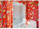 The bathroom has a white tub and toilet, a red floral wall, and a matching red and white shower curtain at 1886 Killdeer Ct, Venice, FL 34293