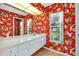 Bright bathroom featuring a large vanity with a sink and drawers, a window, and bold floral wallpaper at 1886 Killdeer Ct, Venice, FL 34293