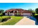 Beautiful single-story home with manicured lawn, tile roof, arched entryway, and brick driveway at 1886 Killdeer Ct, Venice, FL 34293