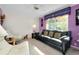 This living room features a black sofa, two white chairs, large window, and is painted in a lilac color at 1886 Killdeer Ct, Venice, FL 34293