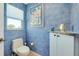 Charming powder room with blue textured walls, toilet, vanity, and natural light from a window at 1886 Killdeer Ct, Venice, FL 34293