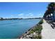 Beautiful waterfront view with a paved walkway alongside the water and lush trees and greenery at 1886 Killdeer Ct, Venice, FL 34293