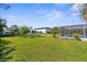 Expansive backyard featuring a well-maintained lawn, fire pit, and partial view of the screened-in pool at 201 Cavallini Dr, Nokomis, FL 34275