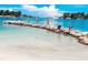 Picturesque beach view of playing on a rock barrier with calm clear water and a sailboat in the background at 201 Cavallini Dr, Nokomis, FL 34275