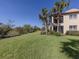 Sprawling green backyard with lush grass and views of trees, bordering a scenic pond and palm trees at 206 Bella Vista Ter # 29A, Nokomis, FL 34275