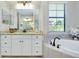 Bright bathroom featuring a soaking tub, vanity with granite top, and bronze fixtures at 20794 Valprato Ct, Venice, FL 34293