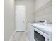 Bright laundry room featuring a side-by-side washer and dryer, tiled flooring, and a white door at 20794 Valprato Ct, Venice, FL 34293