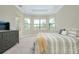Bedroom with tray ceiling, carpeted floor, dresser and windows to let sunlight in at 20794 Valprato Ct, Venice, FL 34293