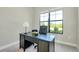 Close-up of home office with dark wood desk, desk lamp and black office chair, with a view of the outside at 20794 Valprato Ct, Venice, FL 34293