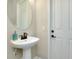 Charming powder room with pedestal sink, decorative mirror, and white paneled door at 20794 Valprato Ct, Venice, FL 34293