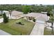 Tan home features a large driveway, spacious front yard with garden and an American flag on a pole at 31 Ramblewood St, Port Charlotte, FL 33953