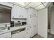 Efficient kitchen with white cabinets and a vintage dishwasher, and great storage spaces at 358 Pineview Dr, Venice, FL 34293
