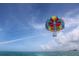Parasailing adventure with colorful parachute soaring above the ocean under blue sky with a group of people enjoying ride at 418 Cerromar Ct # 261, Venice, FL 34293