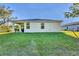 Home's back exterior view showing a well-maintained lawn, patio and trees at 4324 Knowles Ln, North Port, FL 34288