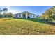 Well-maintained, stucco home featuring a large backyard with lush green grass and a covered patio at 4324 Knowles Ln, North Port, FL 34288