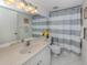 Clean bathroom showcases a light vanity, striped shower curtain, and classic tiled floor at 435 Cerromar Ln # 326, Venice, FL 34293