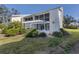 Building exterior featuring a covered lanai, mature landscaping, and manicured lawn at 435 Cerromar Ln # 326, Venice, FL 34293