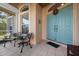 Welcoming front entrance with a charming teal door, decorative wreath, and seating area on the covered porch at 456 Pinewood Lake Dr, Venice, FL 34285
